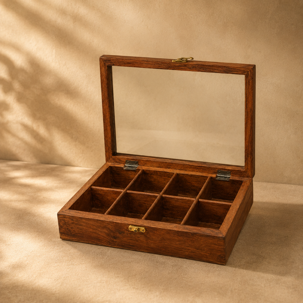 A rectangular wooden jewelry box with a hinged glass lid, shown open to reveal nine interior compartments. The box has a warm medium-brown wood finish with small brass-tone metal latches and hinges, set against a beige textured backdrop with soft shadow overlays.